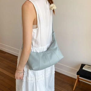 Detail view of light blue leather half-moon bag featuring grainy texture and silver buckle