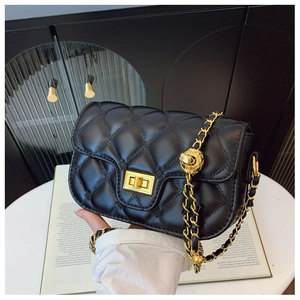 Detailed view of black quilted leather crossbody bag with gold ball chain on book