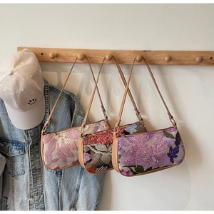 Detail of floral embroidery and sequins on vintage underarm bags hanging on a rack