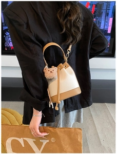 Detail of cream and brown leather bucket bag featuring a cute plush bear charm