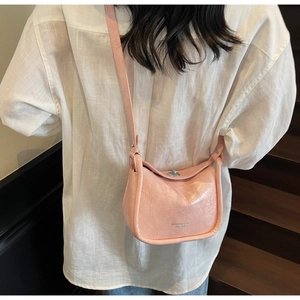 Pink semi-circle crossbody bag with silver twist lock worn by model on stairs