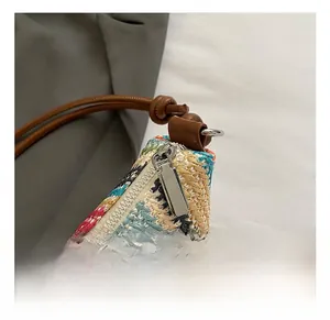 Close-up of colorful woven straw bag with silver zipper and brown leather shoulder strap