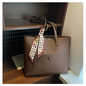 Detail of dark brown lychee grain leather tote bag with brand logo and silk scarf detail
