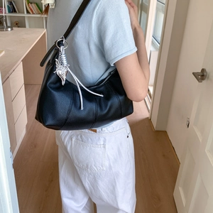 Detail of black pebbled leather hobo bag featuring a decorative silver butterfly charm
