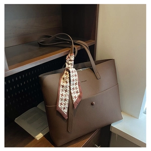 Brown lychee leather tote bag detailed with a houndstooth silk scarf on wooden background