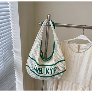 Detail of white crochet tote bag featuring green knitted text and mesh texture details