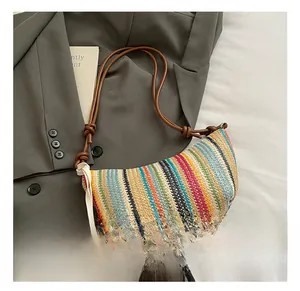 Rainbow striped straw shoulder bag with a sunflower charm on a grey blazer backdrop