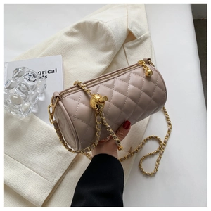 Détail du sac cylindre taupe matelassé avec chaîne dorée et pendentif sphérique