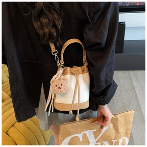 Mini bucket bag in white lychee pattern and brown leather on model with bear charm
