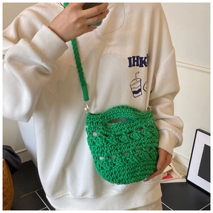 Detail of hand-woven green knit bucket bag showing textured crochet mesh and strap