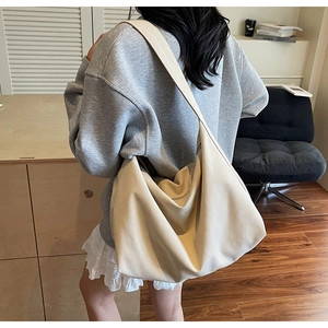 Dettaglio di una grande borsa hobo bianco panna con tracolla larga indossata da modella