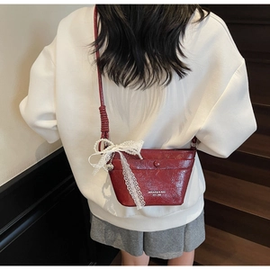Detail of burgundy bucket bag with white lace bow and silver heart pendant charm