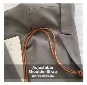 Detail of adjustable leather-textured shoulder strap with knot fixing on a woven straw bag