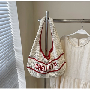 Close-up of cream knitted tote bag with red CHELIYP text and sturdy handle detail