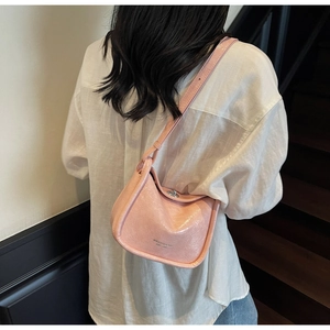 Detail of light pink patent leather mini bag with silver knob and printed logo text