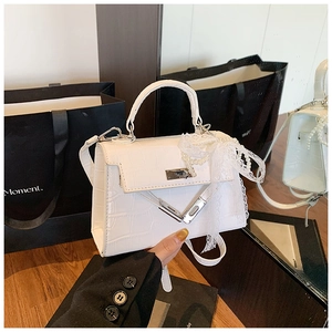 Close-up of white crocodile embossed Kelly bag with pearl lace bow and silver lock detail