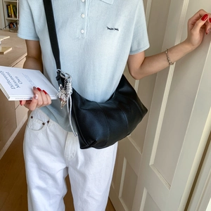 Detail of black crescent crossbody bag with silver butterfly charm and lychee texture leather