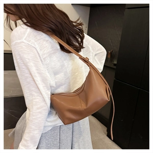 Detail of adjustable strap and smooth brown leather texture on a crescent shoulder bag