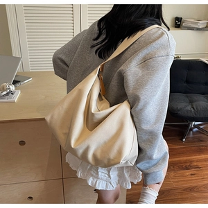Dettaglio della borsa hobo in tela beige sulla spalla per lo stile quotidiano e minimalista