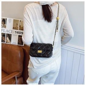 Close-up of black quilted shoulder bag with gold chain strap and metal swivel lock