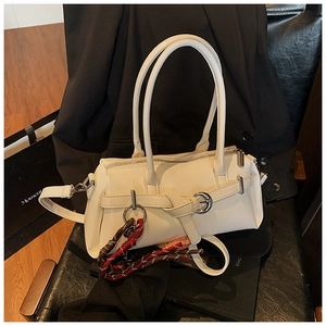 Detail of white leather handbag featuring metal ring buckle and colorful braided rope pendant