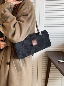 Sac baguette vintage en jacquard noir avec bandoulière en cuir marron sur l'épaule