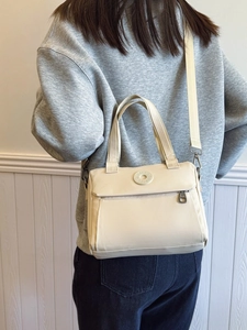 Minimalist beige nylon crossbody bag with adjustable wide strap and circular logo detail