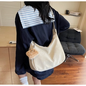 Detail of cream leather hobo bag with cute animal embroidery and plush pendant