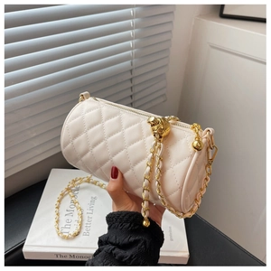 Détails du sac cylindrique matelassé crème avec chaîne dorée et breloque métallique