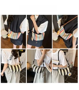 Detail view of crescent straw bag with colorful stripes and floral charm on a model