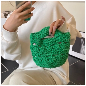 Detail of a bright green hand-knitted bucket bag with textured rope weave and handle