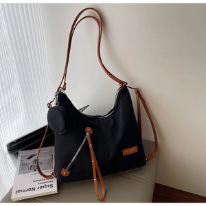 Detail of black nylon hobo bag with brown leather straps and small round pouch