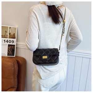 Detail of black quilted leather crossbody bag with gold-tone ball and chain strap