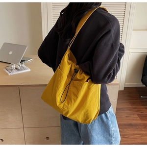 Detail view of large yellow drawstring bucket bag with side pockets and nylon fabric