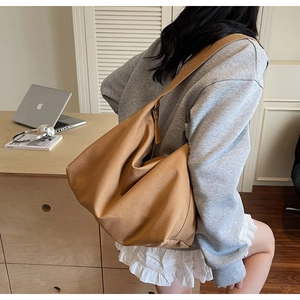 Vista dettagliata della borsa tote in tela capiente indossata da una modella in interno