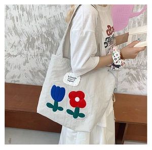 Detail of embroidered floral patch and inspirational text on a canvas tote bag