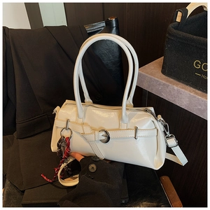 Detail of white patent leather handbag with decorative buckle and woven charm