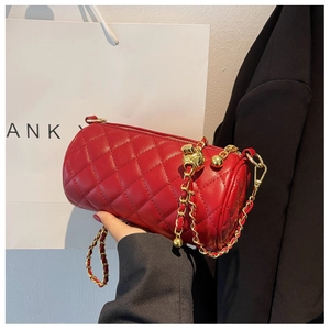 Détail du sac cylindre matelassé rouge avec chaîne dorée et boule dorée décorative