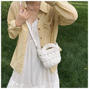 Detail of white handmade woven bucket bag showing hollow knit texture and braided strap