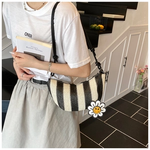 Detail of woven crescent bag with black stripes and a cheerful sunflower charm accessory