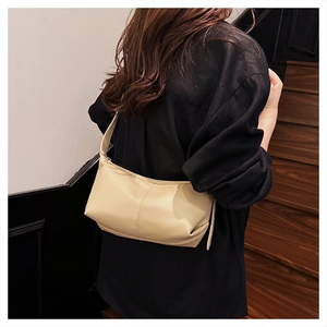 Detail of minimalist beige dumpling bag with vertical stitching on leather texture