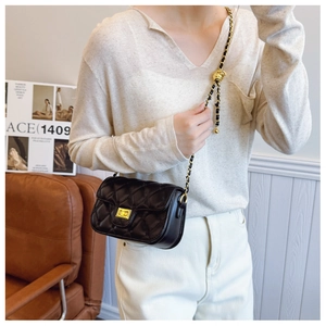 Close-up of black quilted crossbody bag with adjustable golden ball chain on model