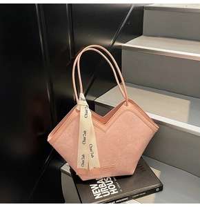 Pink tote bag detail with textured leather surface and elegant printed silk scarf on handle