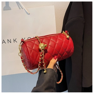 Détail du sac cylindrique matelassé rouge avec chaîne dorée et boucle de réglage ronde