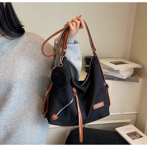 Detail of black nylon shoulder bag with brown leather straps and small round coin purse