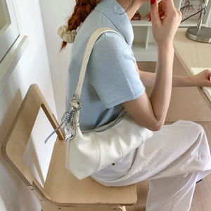 Detail of white lychee texture shoulder bag with silver butterfly charm and knot detail