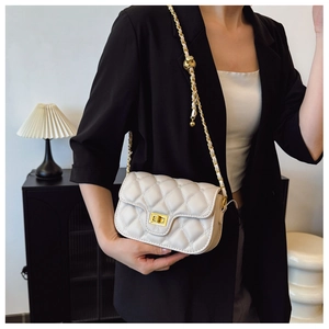 Detail of quilted white crossbody bag with gold chain and ball clasp on model