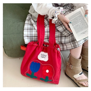 Detail of red canvas tote bag with tulip embroidery and fearless quote inscription