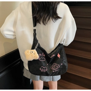 Detail of black dumpling crossbody bag featuring pink cartoon cat print and plush pendant
