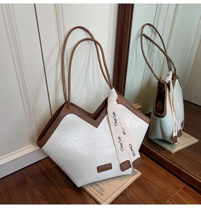 Detail of white crocodile texture tote bag with V-shaped opening and decorative ribbon